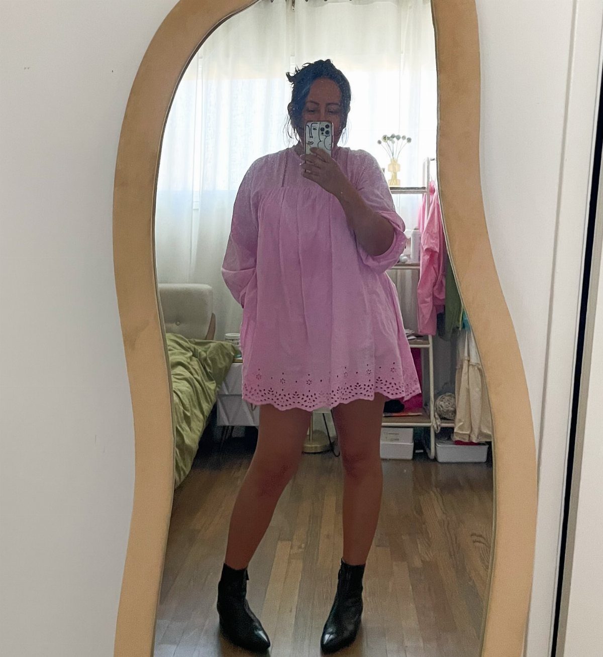 A woman in a pink dress and black ankle boots posing for a mirror selfie.