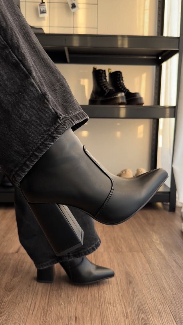 Black pointed-toe ankle boots with a block heel worn with dark grey denim jeans.