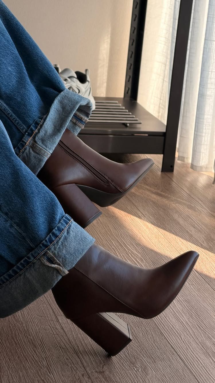 Cuffed blue denim jeans paired with dark brown pointed-toe block heel ankle boots.