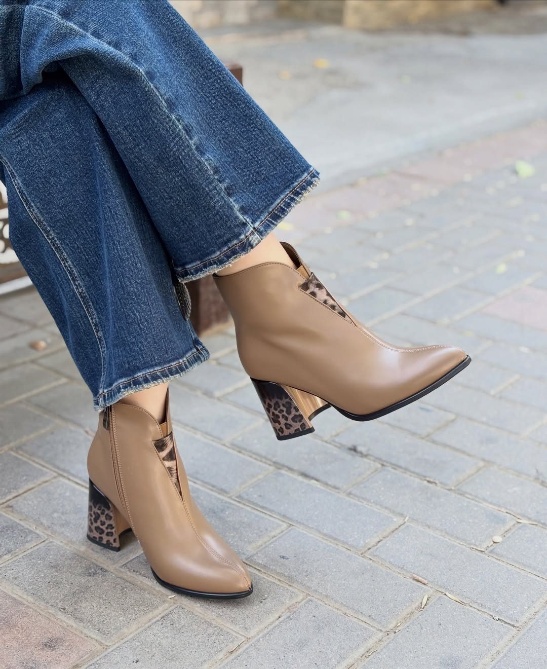 Tan pointed-toe ankle boots with leopard print heels worn with blue denim jeans.