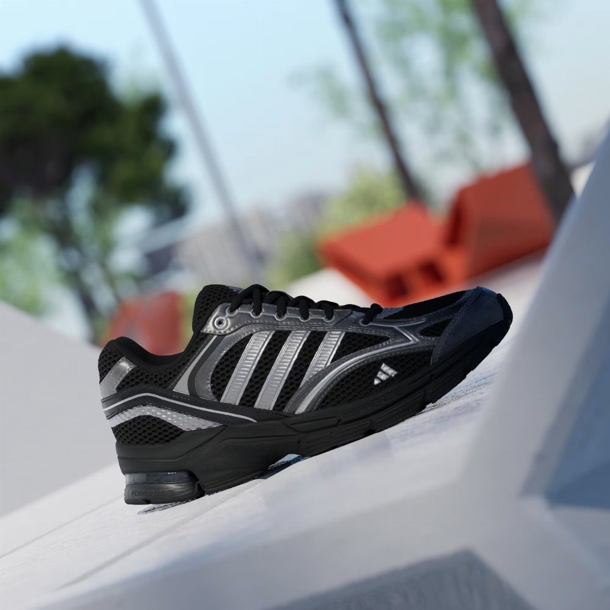 A black and silver athletic sneaker resting on a white geometric surface outdoors.