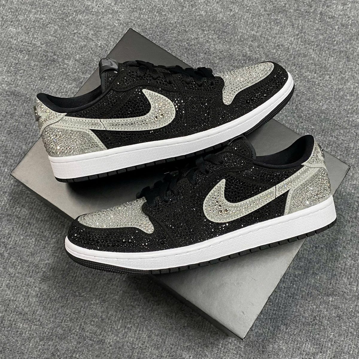 Black and silver rhinestone-encrusted sneakers resting on a black shoebox.