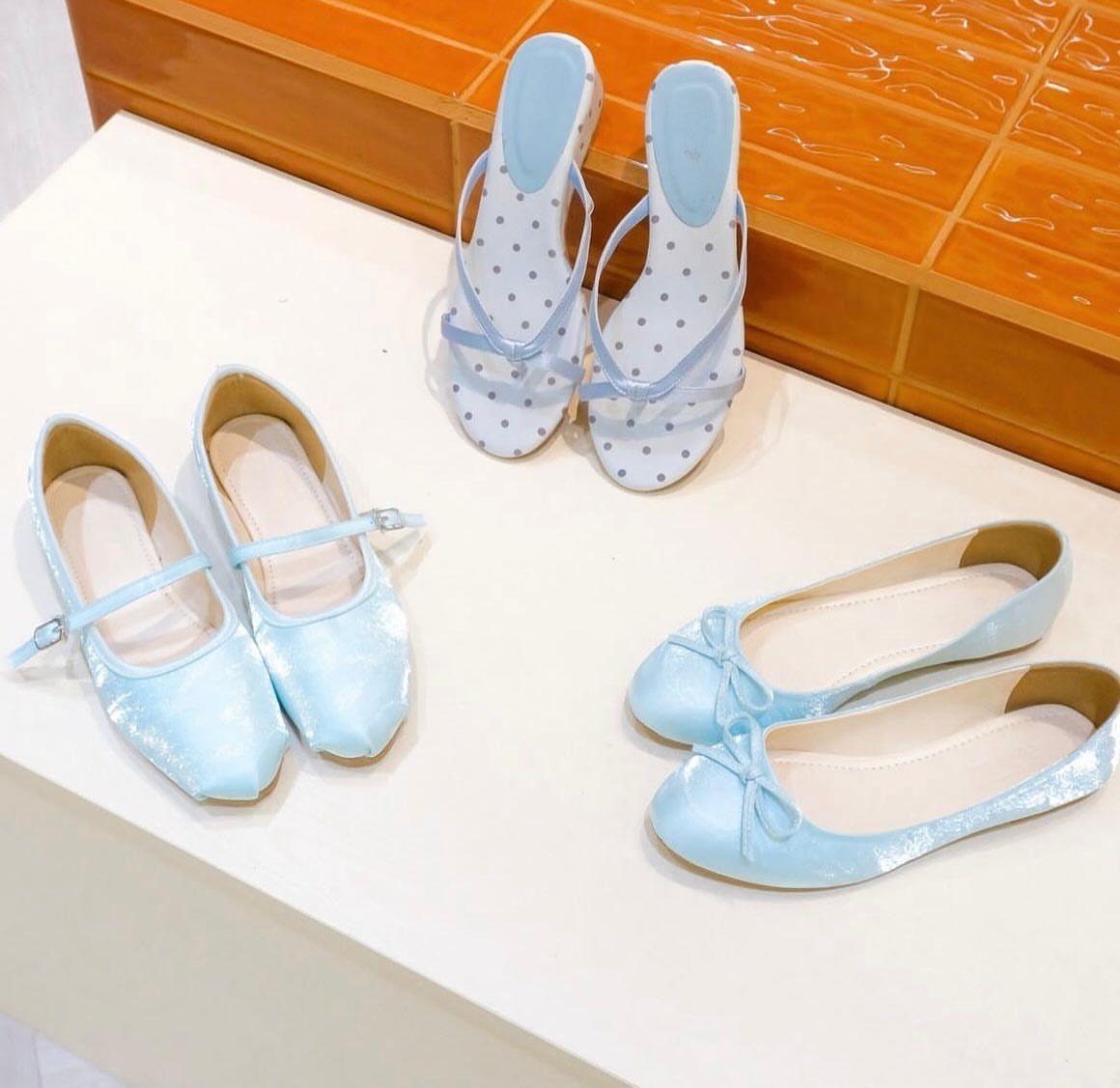 Light blue velvet Mary Jane flats and other light blue footwear arranged on a white surface.