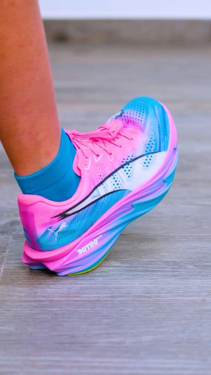 Pink and blue Puma running shoe with a prominent curved rocker bottom sole.
