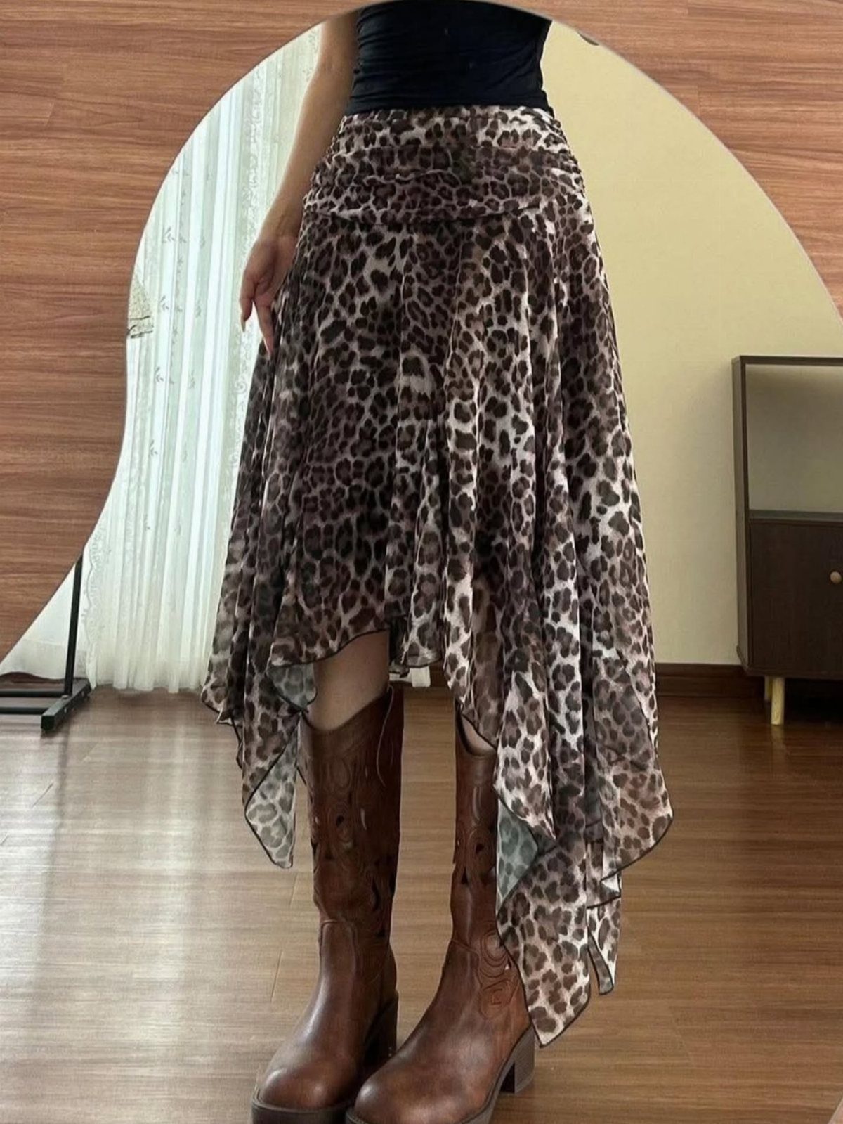Person wearing a leopard print layered chiffon skirt and brown leather cowboy boots.
