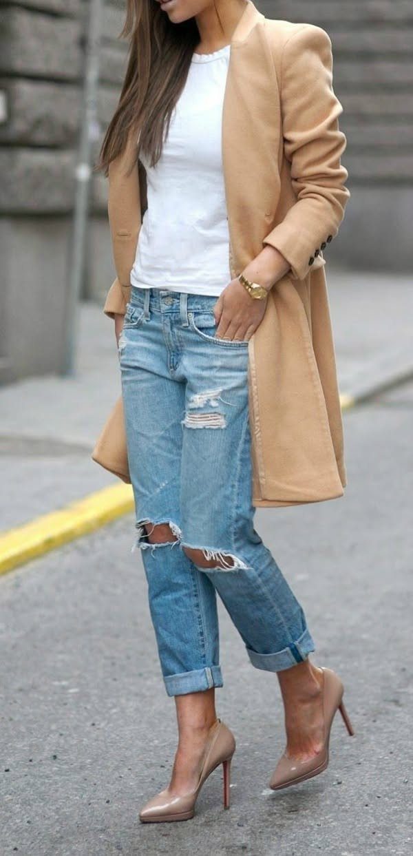 A woman wearing distressed boyfriend jeans, a tan coat, and beige pointed-toe high heels.