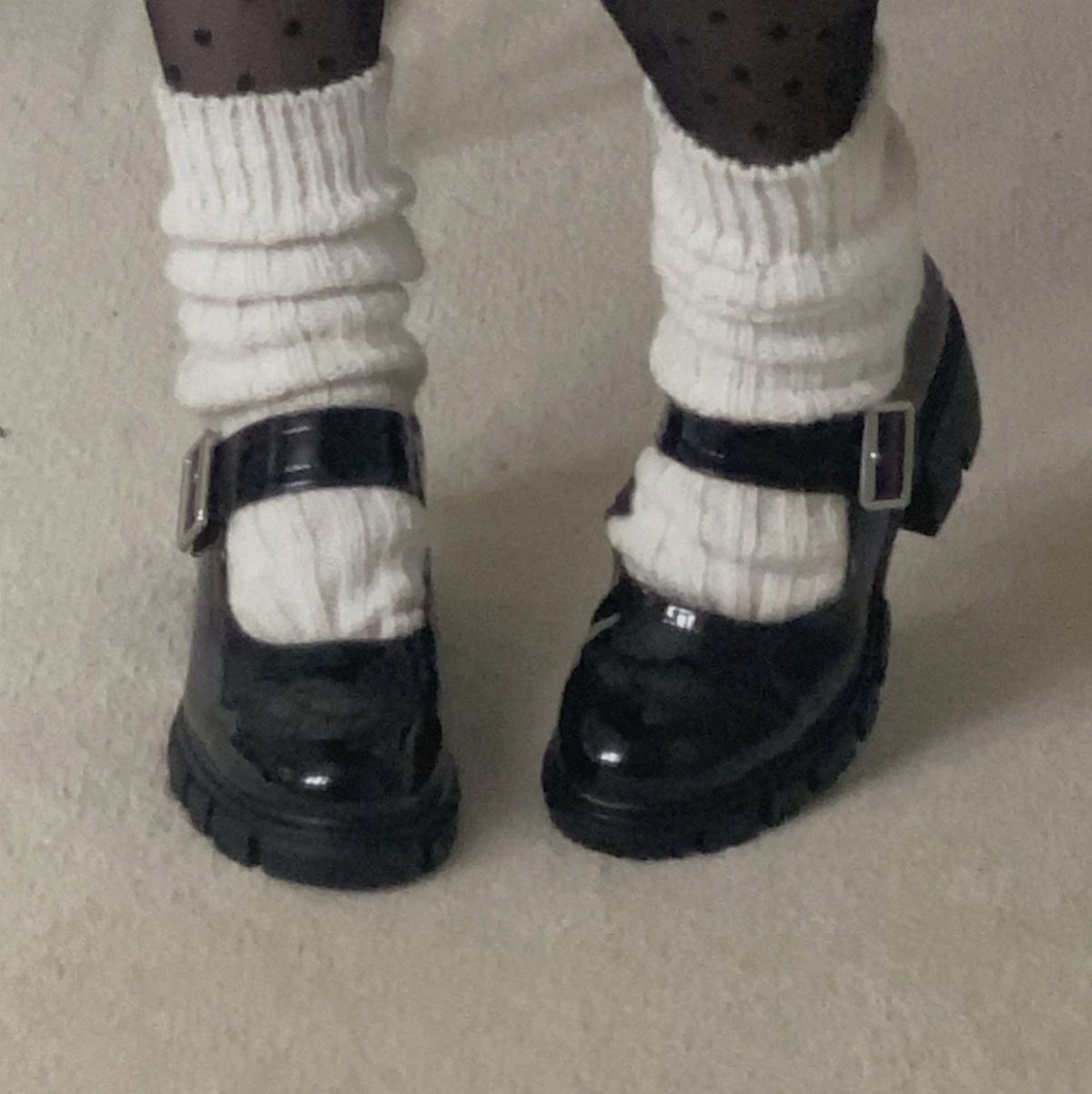 Black patent leather Mary Jane shoes worn with thick white ribbed socks and polka dot tights.