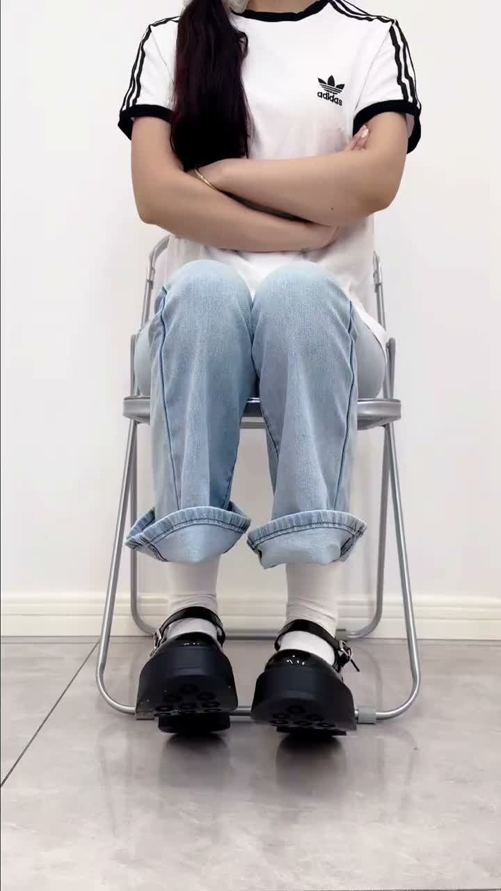 Person sitting on a chair wearing black Mary Jane shoes with white crew socks.
