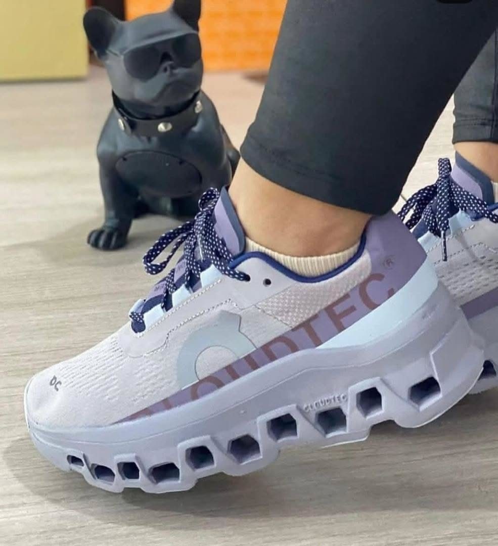 A person wearing light purple On CloudTec athletic sneakers while standing on a light floor.