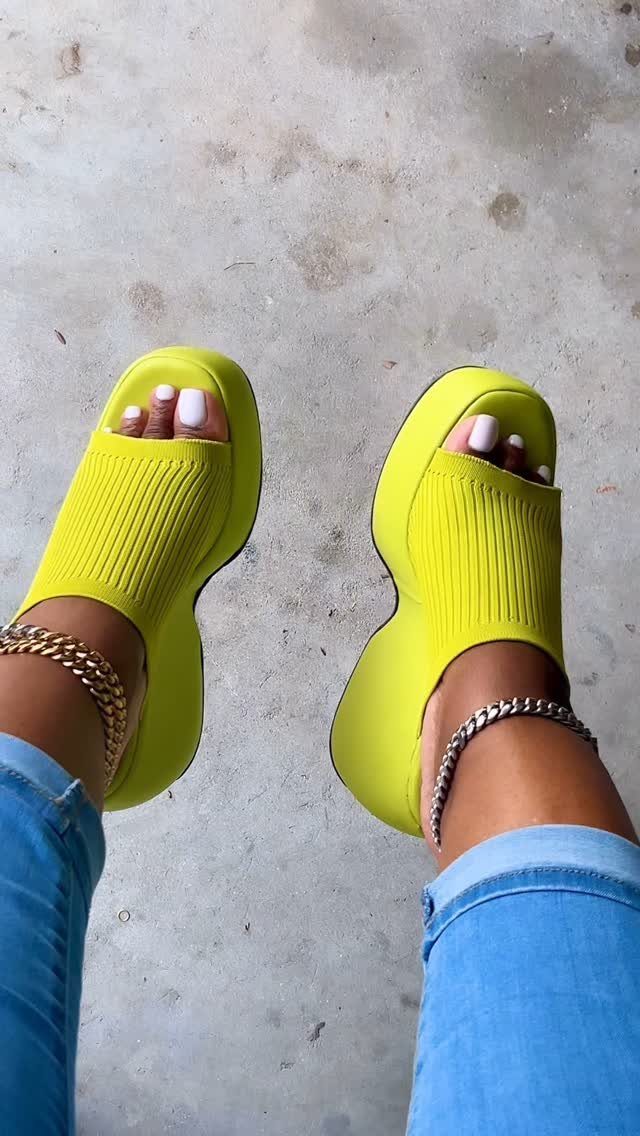 Lime green platform wedge sandals worn by a person with blue jeans and anklets.