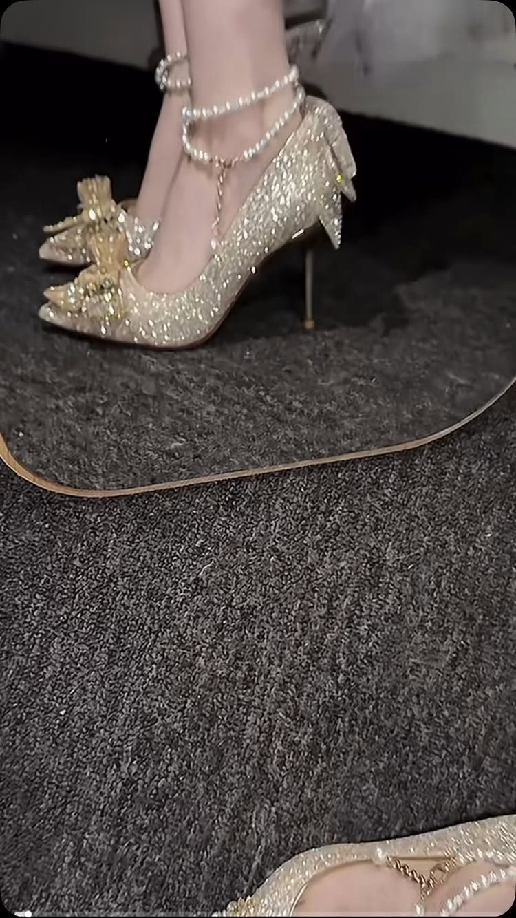 Champagne gold glittery pointed-toe stiletto pumps with pearl ankle straps and decorative bows.