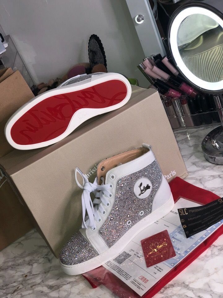 Silver glitter high-top sneakers with white laces and a bright red sole on a shoebox.