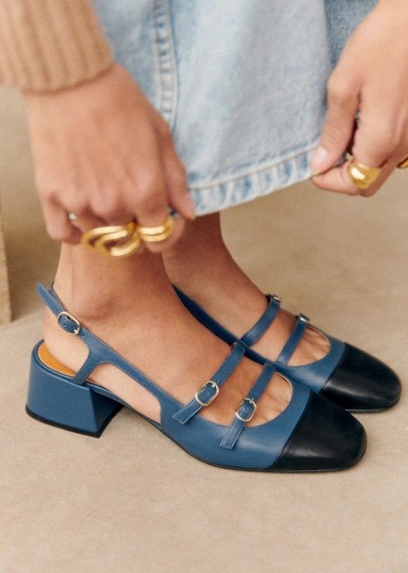 Blue and black block heel Mary Jane shoes with silver buckles worn by a person.