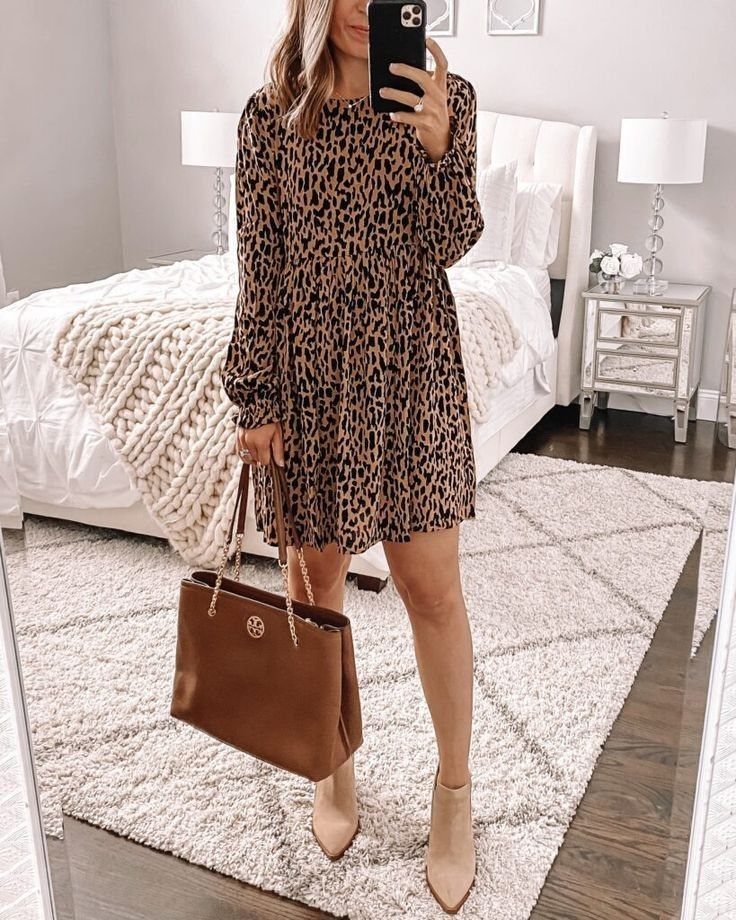 Woman wearing a leopard print brown dress, beige ankle boots, and carrying a brown leather tote bag.