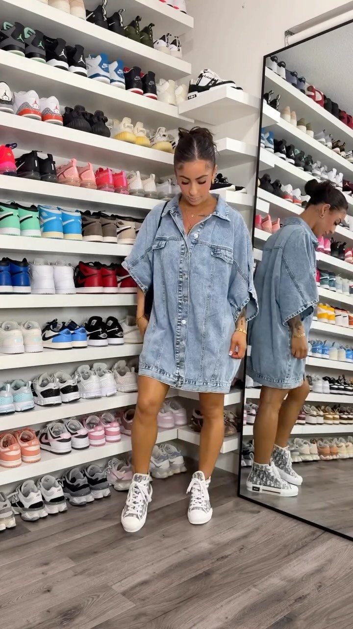 Woman in a denim shirt dress and white sneakers standing in a shoe store.