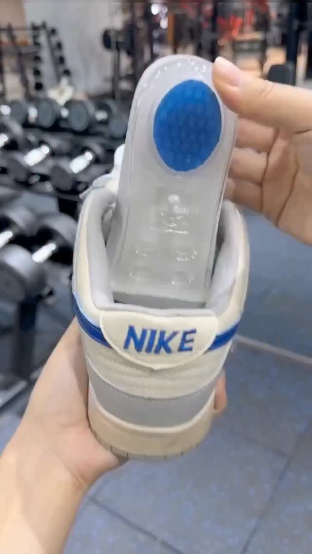A person holding a white Nike shoe to reveal a clear insole with blue heel padding.