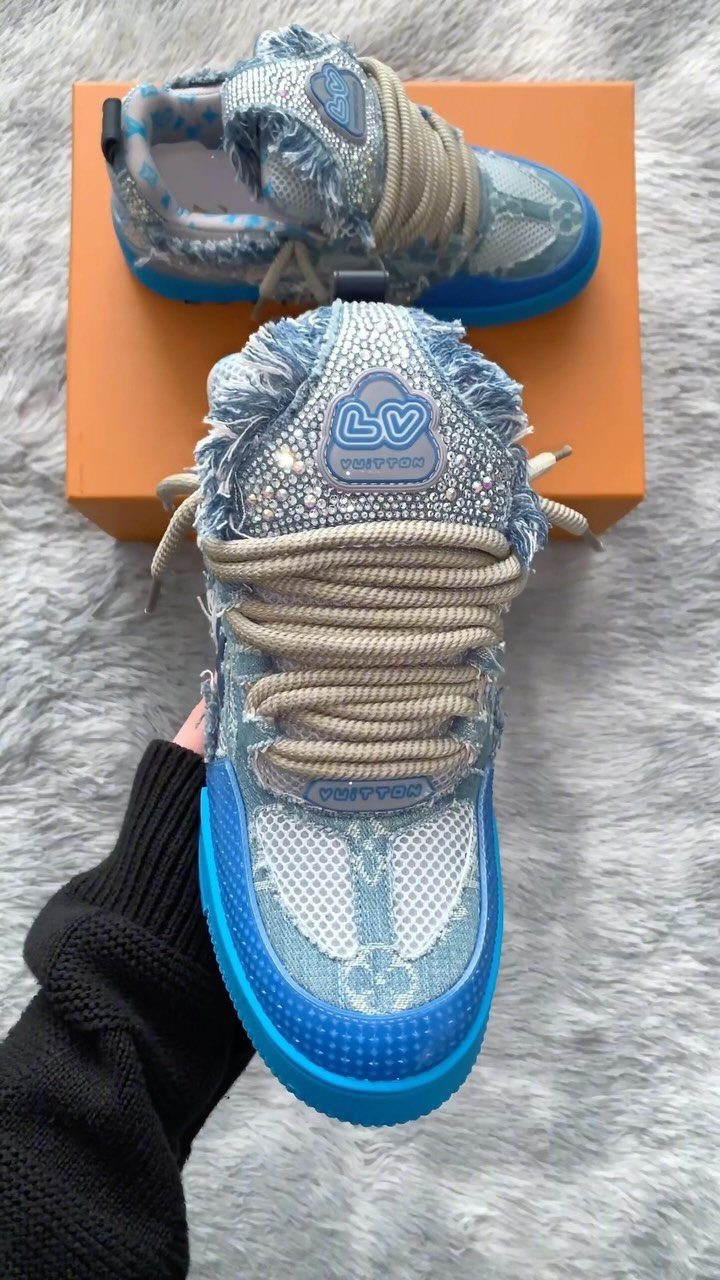 Sparkling blue sneakers with rhinestone embellishments and frayed fabric sitting on an orange box.