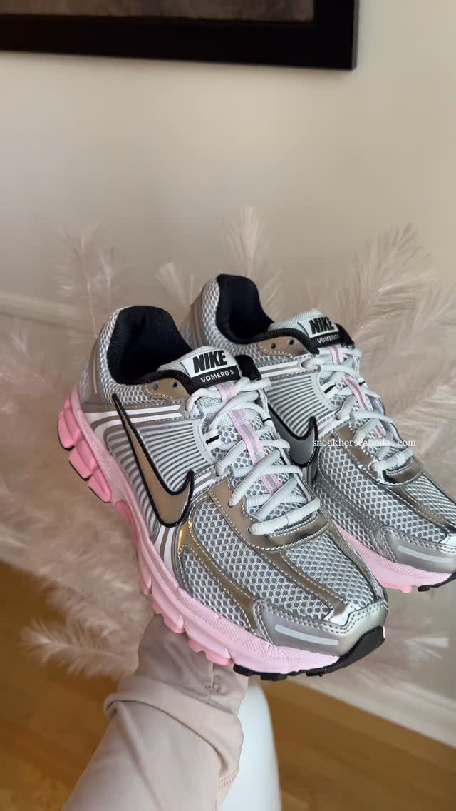 Silver and pink Nike running sneakers held up against a white background.