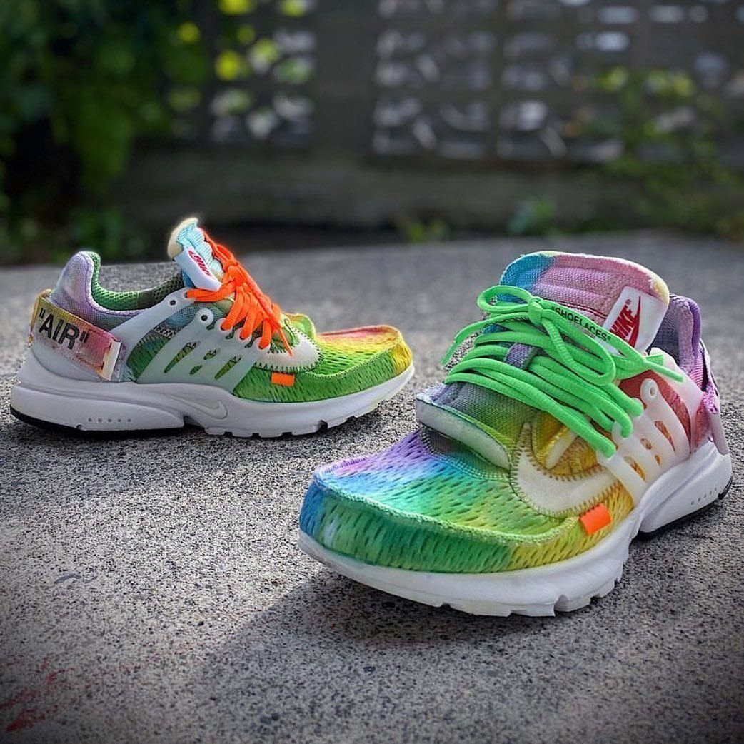 Two colorful tie-dye athletic sneakers resting on a grey concrete ground outdoors.