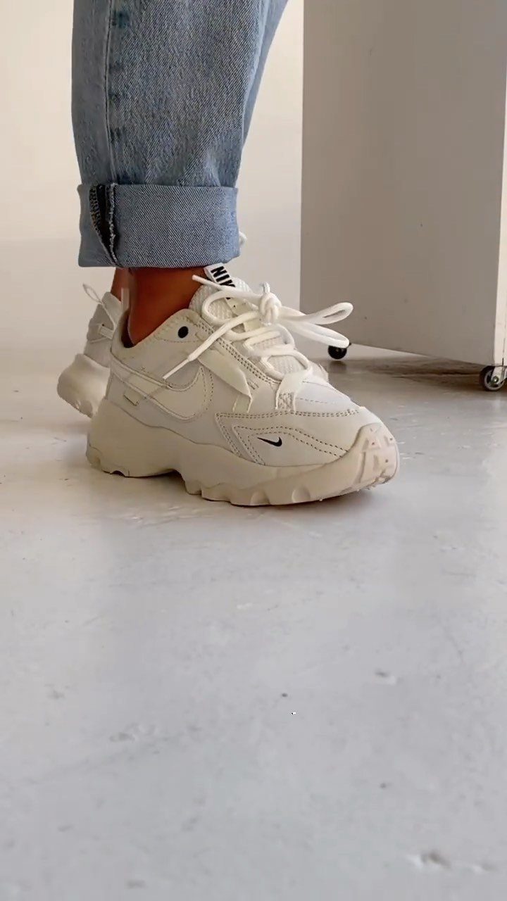 White Nike TC 7900 sneakers with platform soles worn with light blue denim jeans.