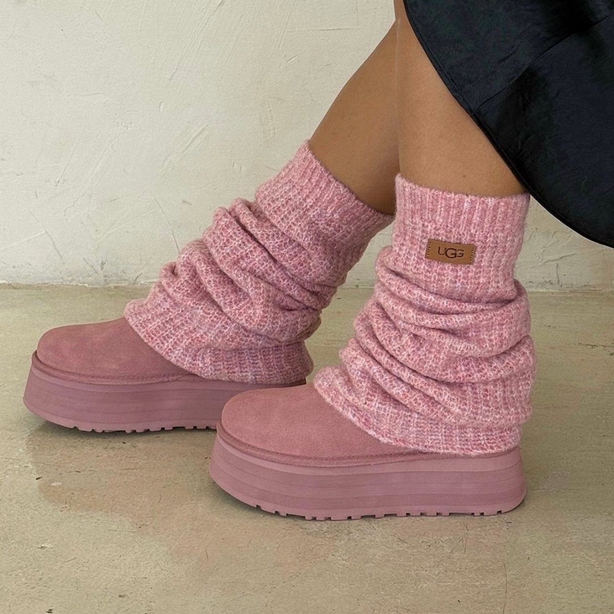 Pink platform Ugg boots worn with thick pink knit leg warmers on a person's feet.