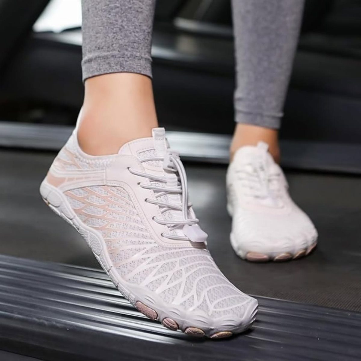 Light pink mesh zero drop sneakers worn by a person on a treadmill.