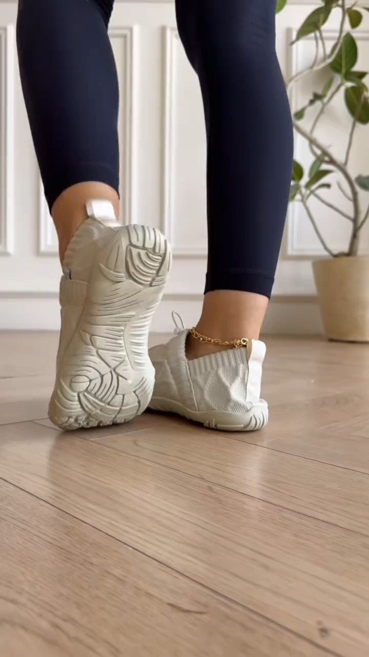 Person wearing white zero drop sneakers and dark blue leggings on a wooden floor.